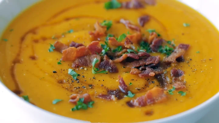 Roasted Butternut Squash Soup 12 Serve Creamy roasted butternut squash soup garnished with a sprinkle of herbs and a drizzle of olive oil in a rustic bowl.