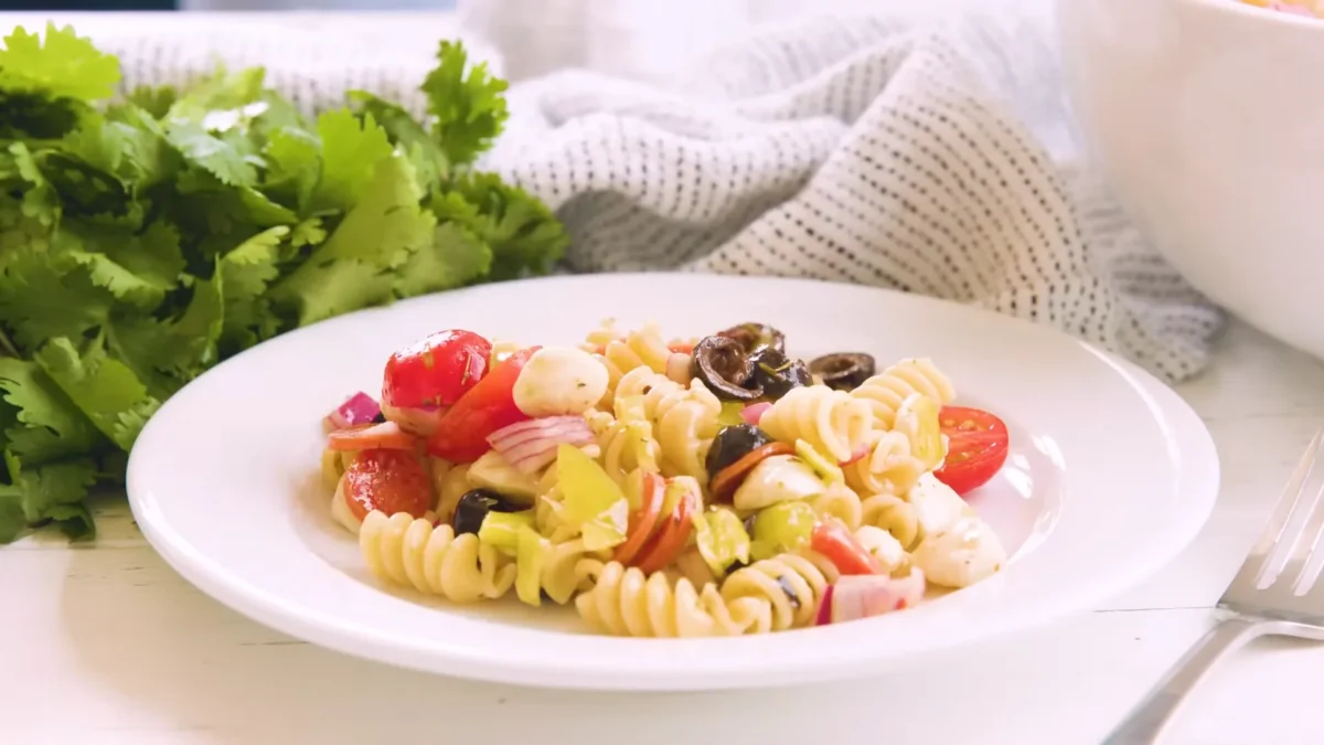 Italian Pasta Salad 12 Chill or Serve Delicious Italian pasta salad with fresh tomatoes, olives, and feta cheese, beautifully arranged in a bowl.