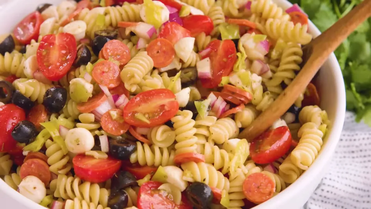 Italian Pasta Salad 13 Chill or Serve Delicious Italian pasta salad with fresh tomatoes, olives, and feta cheese, beautifully arranged in a bowl.