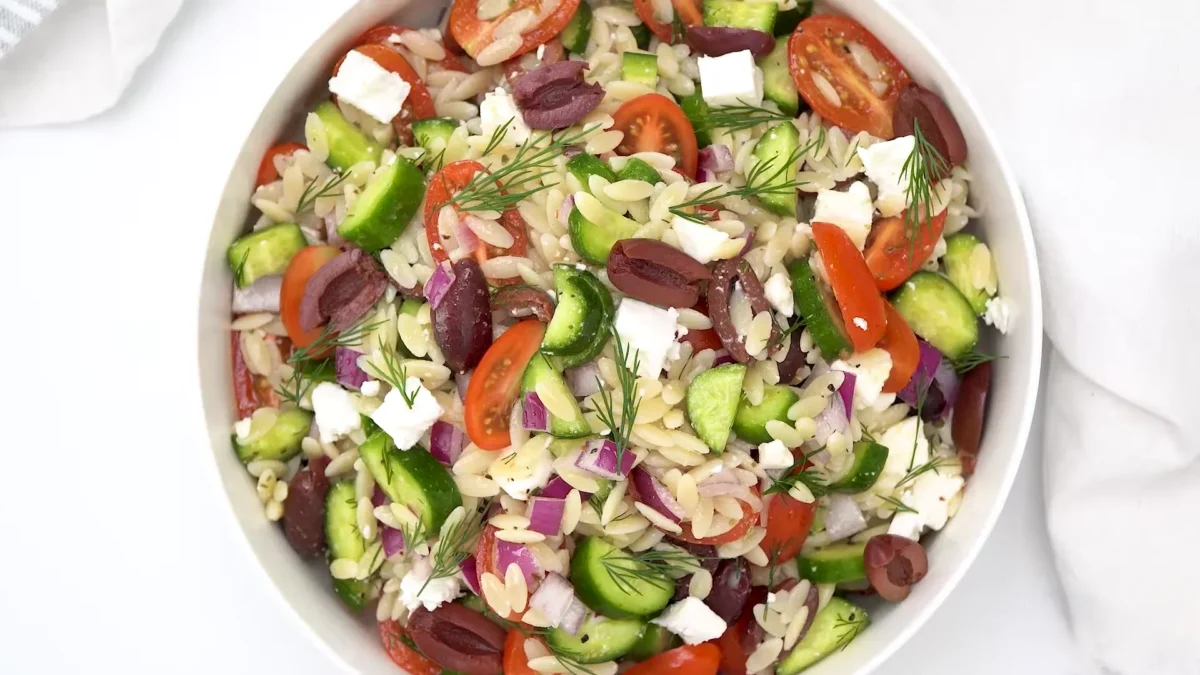 Spinach Greek Orzo Salad 2 A delicious Spinach Greek Orzo Salad showcasing fresh spinach, diced tomatoes, olives, and feta cheese, beautifully arranged.