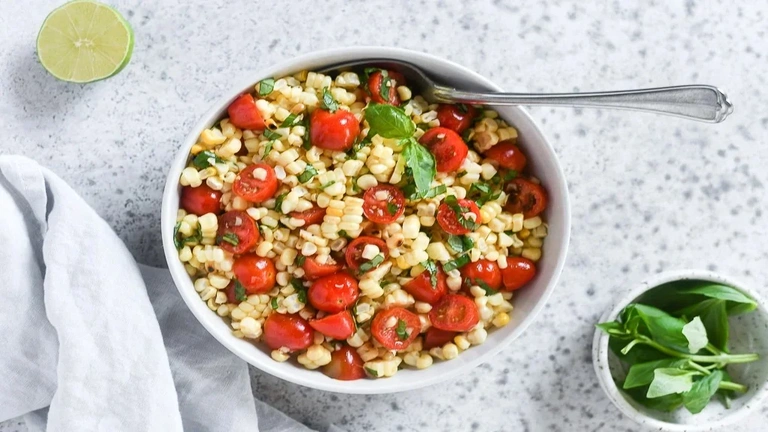 Corn and Tomato Salad 2 A vibrant corn and tomato salad featuring fresh corn kernels, ripe tomatoes, and a sprinkle of herbs in a bowl.
